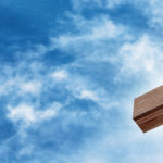Wooden Cross with a Bright Blue Sky and Sun